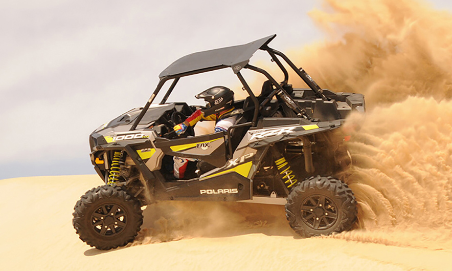 Guests driving Polaris RZR dune buggy over Dubai dunes